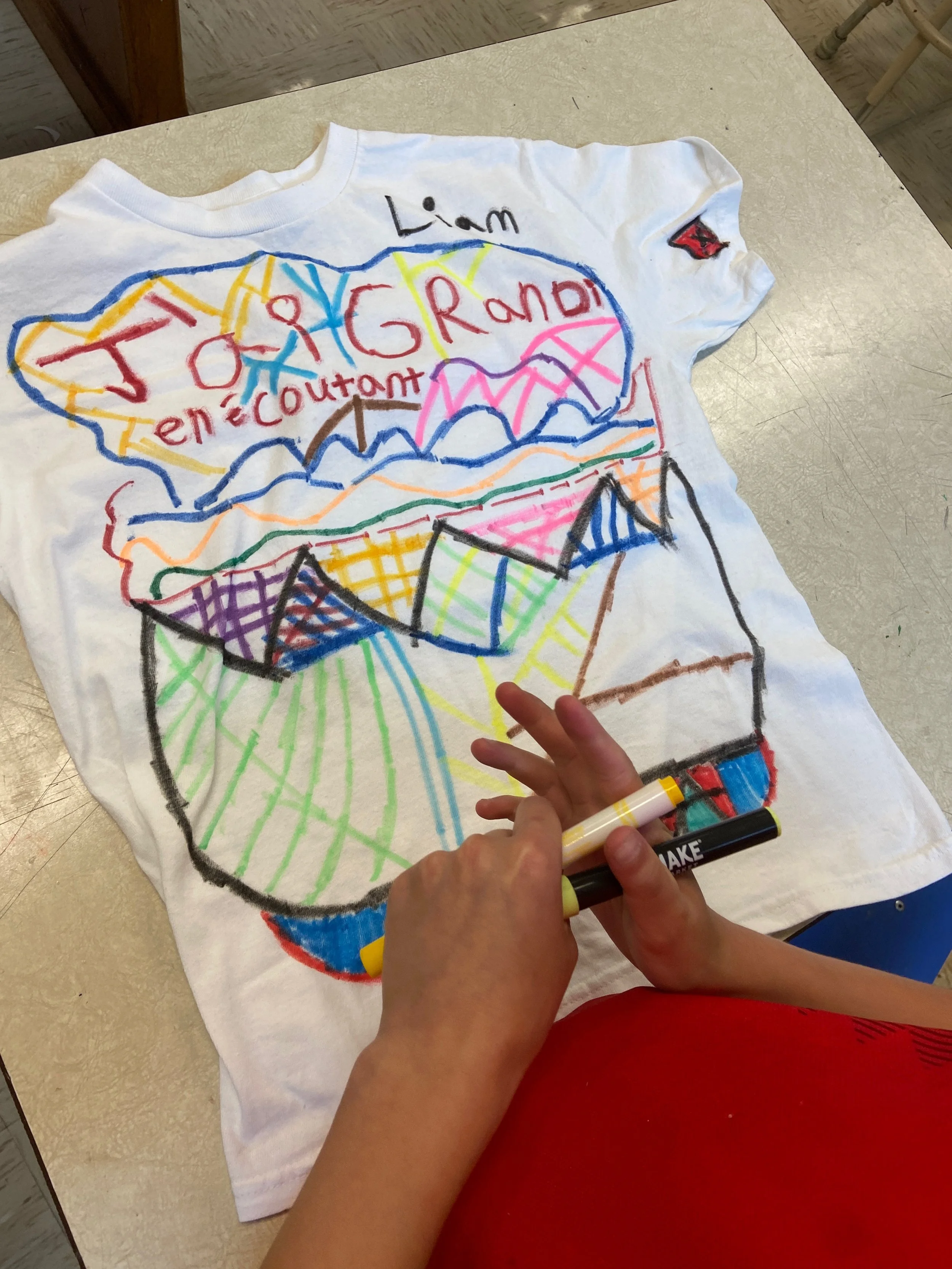 Dessin coloré d'une boîte de popcorn avec un nuage au-dessus, écrit en français 'Liam', et des mots 'J'aime beaucoup en rencontre' à l'intérieur du nuage.