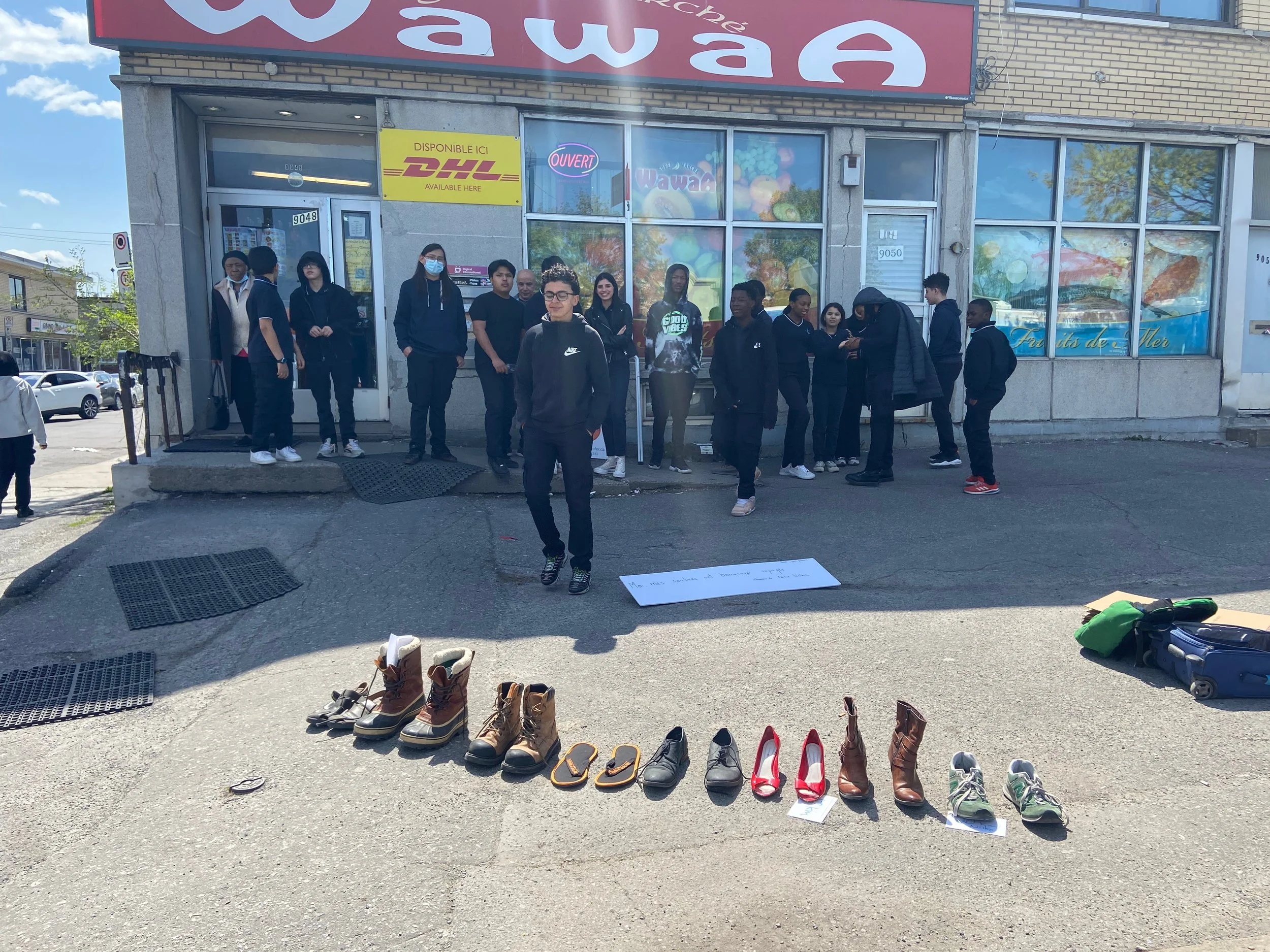 Groupe de personnes faisant une manifestation devant un supermarché, avec des chaussures exposées au sol.
