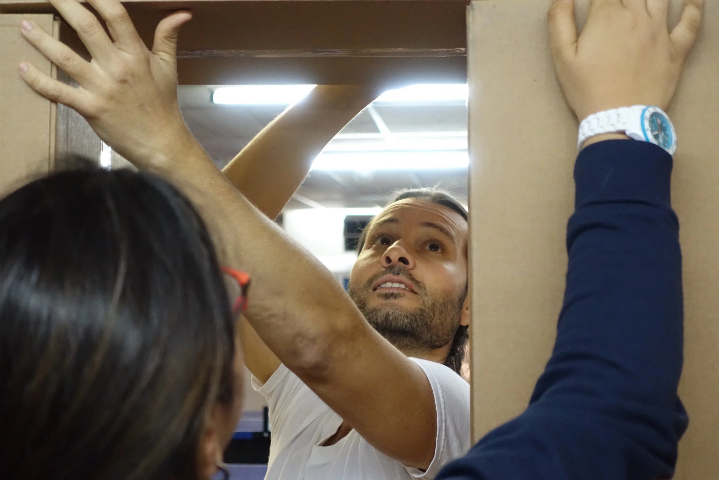 Deux personnes installant une étagère en utilisant une perceuse électrique dans un meuble en bois.