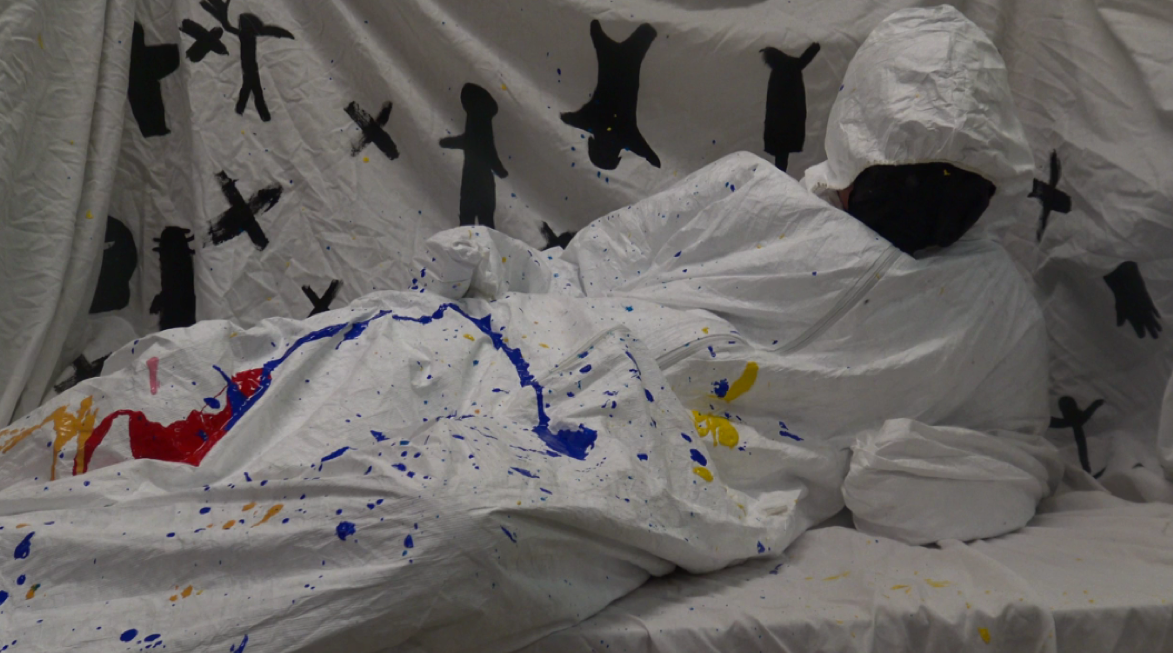 Personne déguisée en fantôme, recouverte d'une couverture blanche, dans un décor avec des silhouettes d'enfants en noir sur un fond blanc avec des taches de peinture colorées.