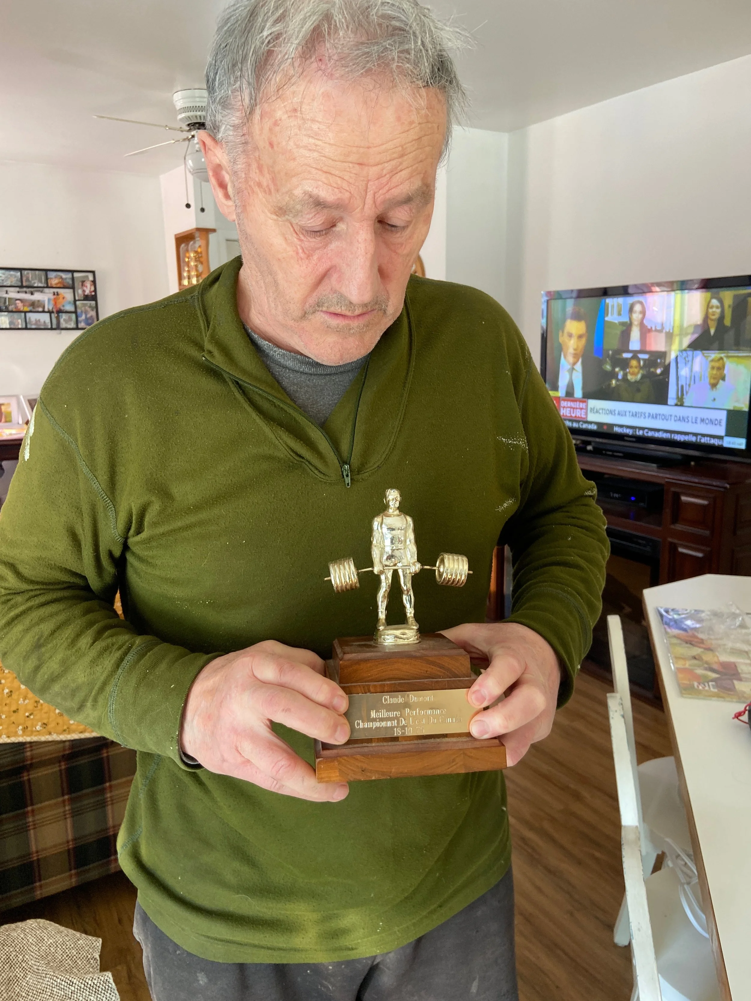 Un homme tenant un trophée en forme d'un homme soulevant une barre avec des haltères.