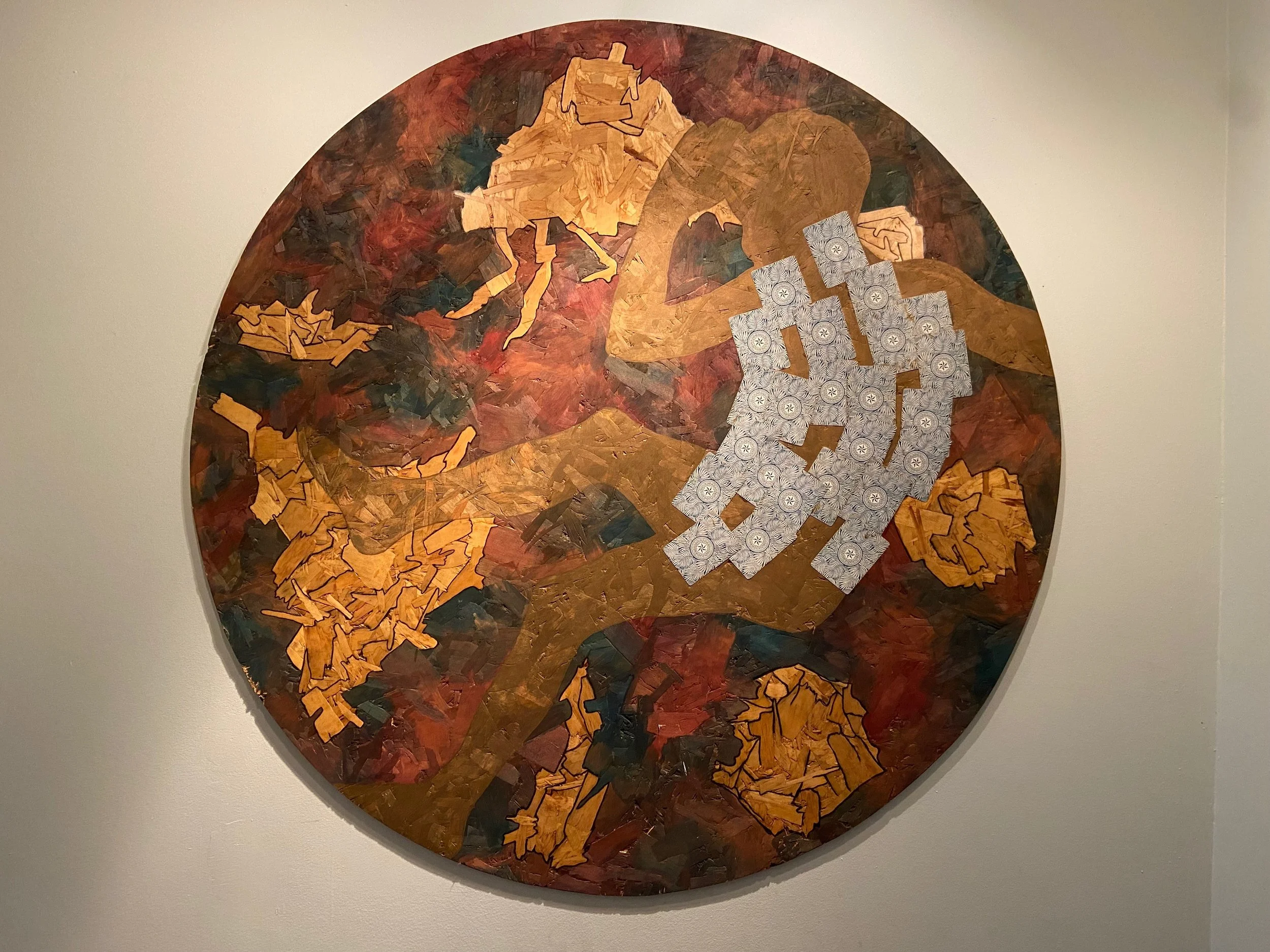 Tableau abstrait rond avec des formes en fougère ou feuillages en couleurs chaudes, accompagné d'une main en forme de collage de motifs circulaires gris.