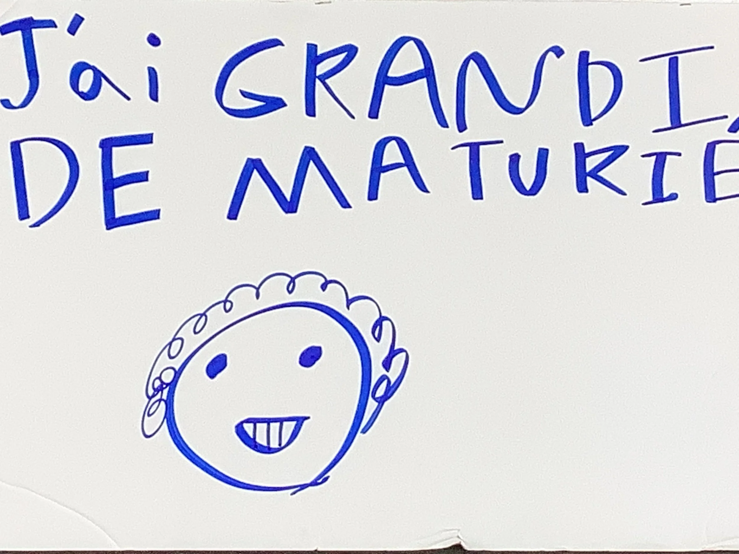 Un dessin à la main en bleu avec le texte 'J'ai grandi de nature' et un visage souriant dessiné à côté.