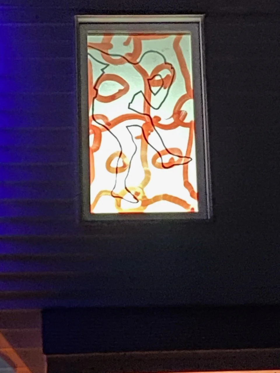 Une fenêtre avec une œuvre d'art moderne abstraite composée de lignes noires et d'ondulations orange et jaune sur un fond blanc