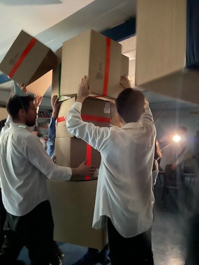 Gens manœuvrant des cartons lors d'une activité de groupe en intérieur.