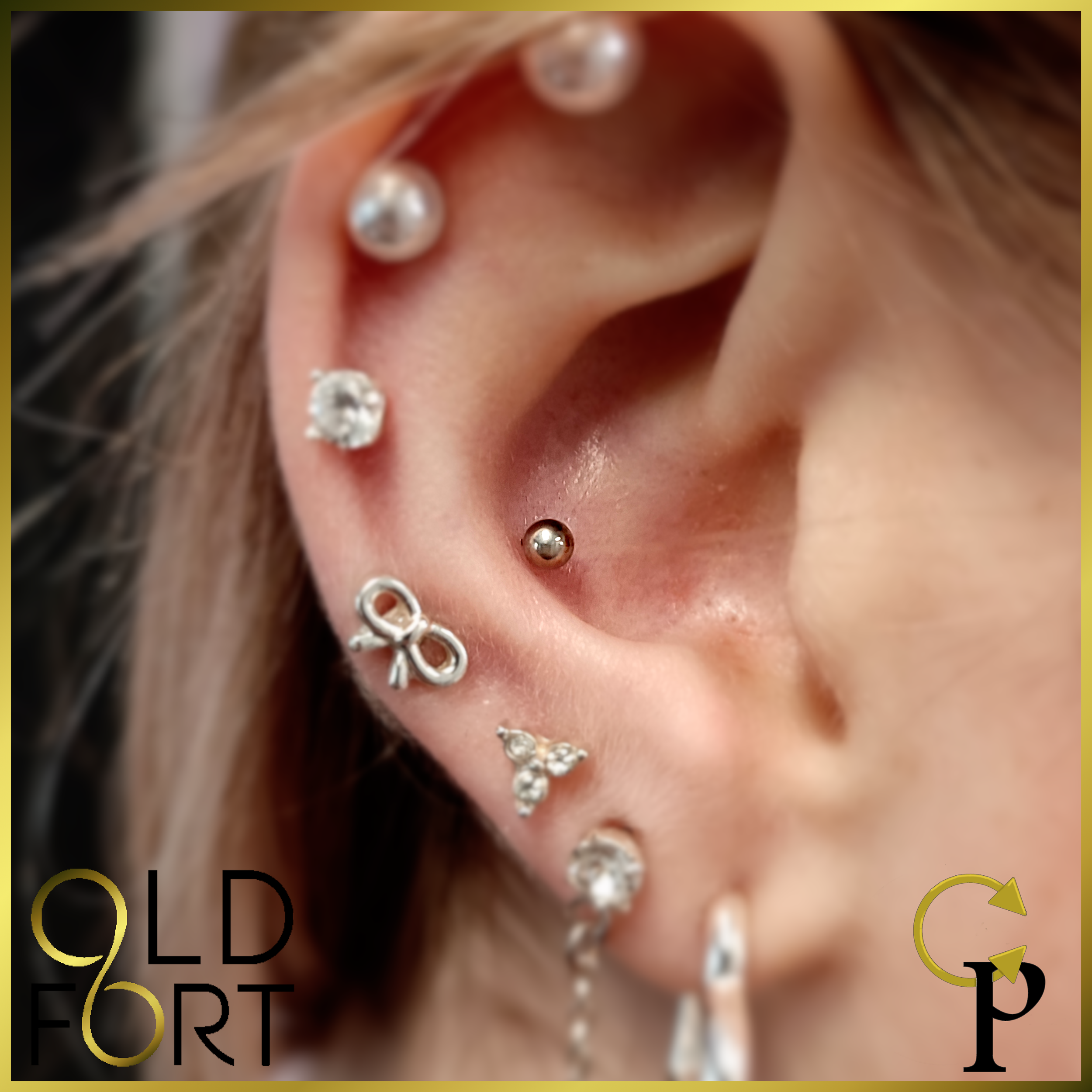 Close-up of a person's ear with multiple piercings, including a helix, conch, and lobe, decorated with various silver and diamond earrings.