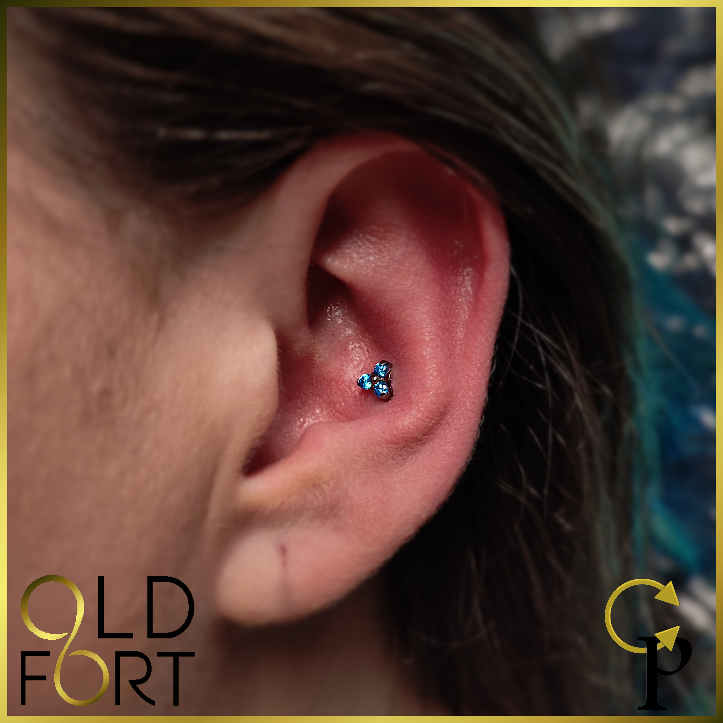 Close-up of a person's ear with a small blue gemstone triple helix cartilage piercing