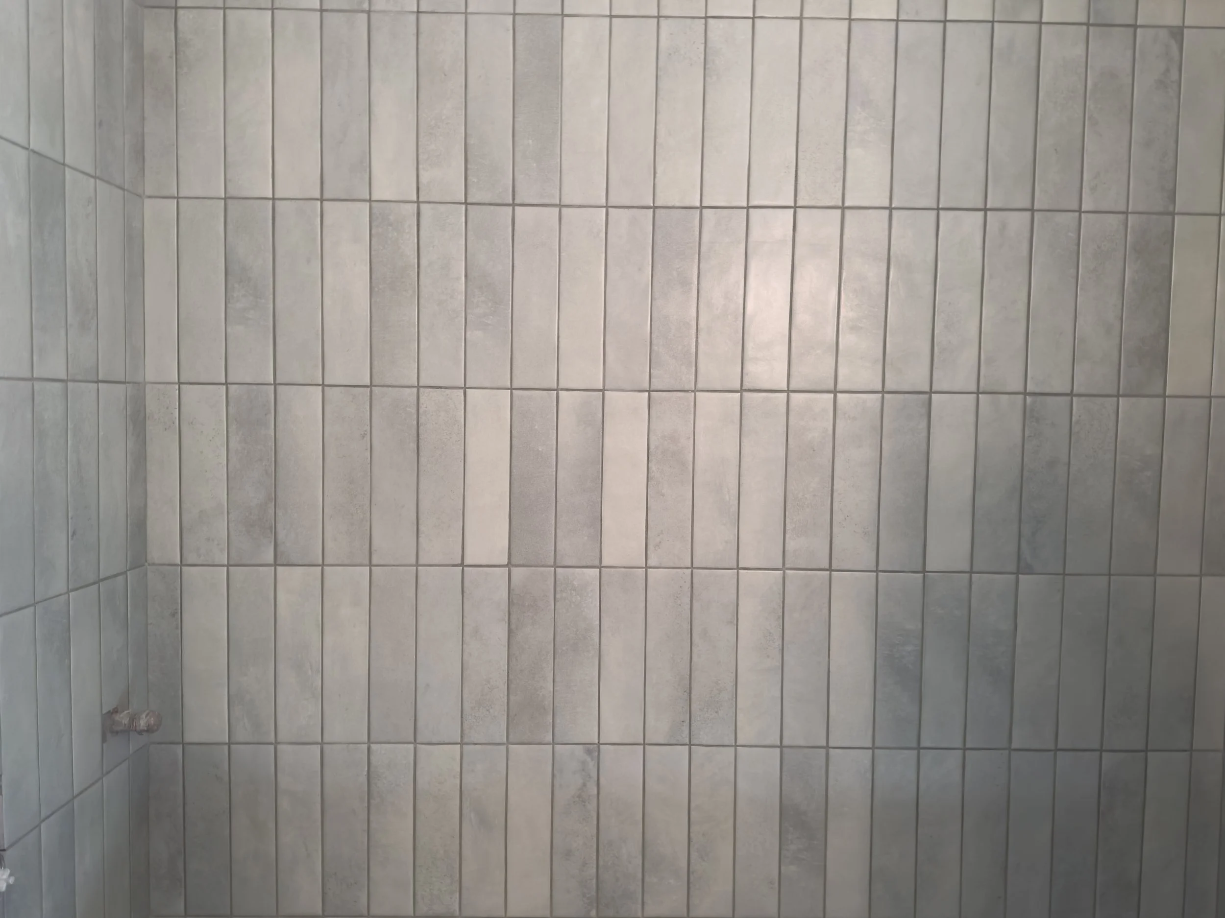 Vertical rectangular gray tiles on a wall.