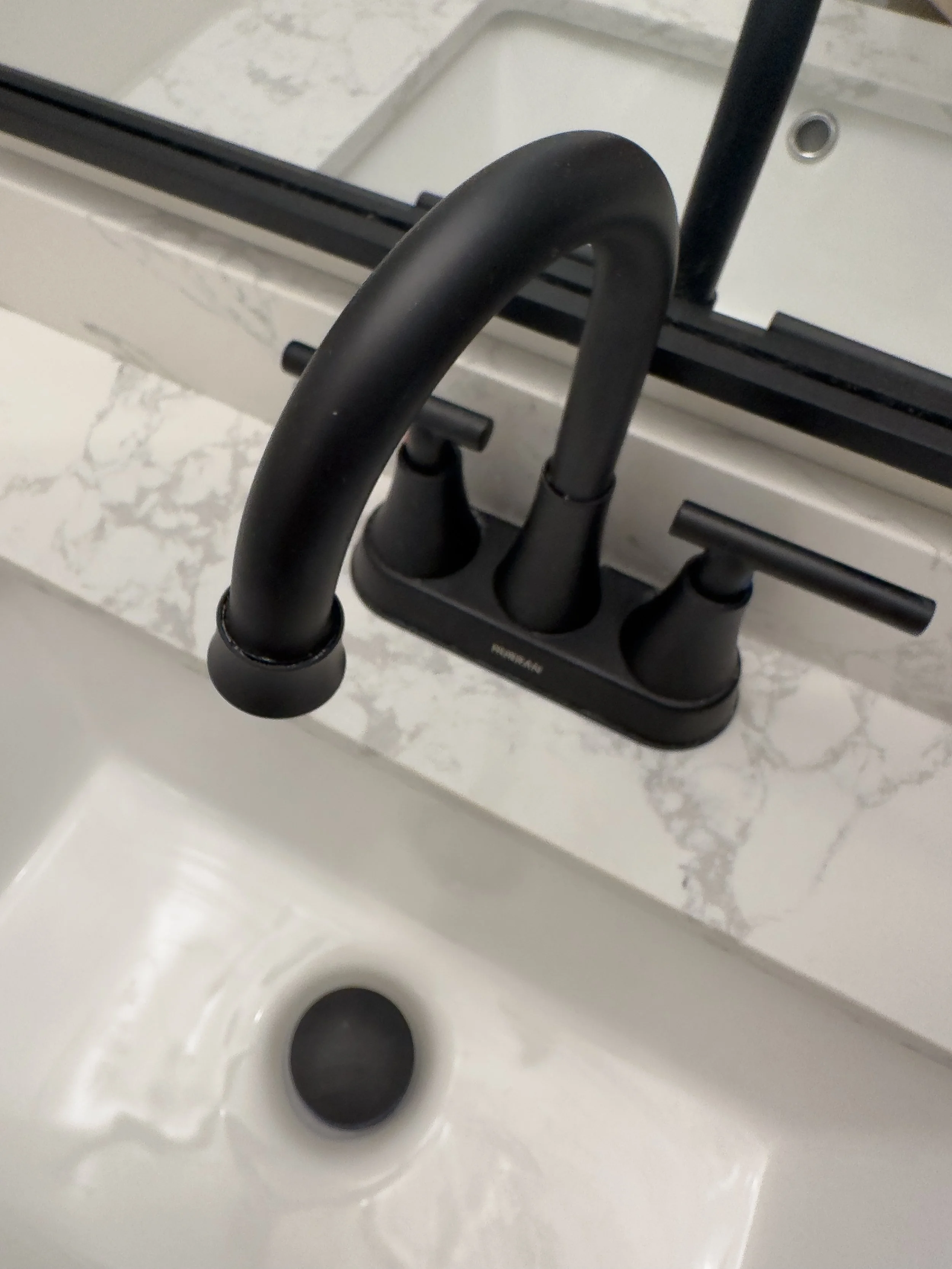 Black bathroom faucet with a marble countertop and white sink.