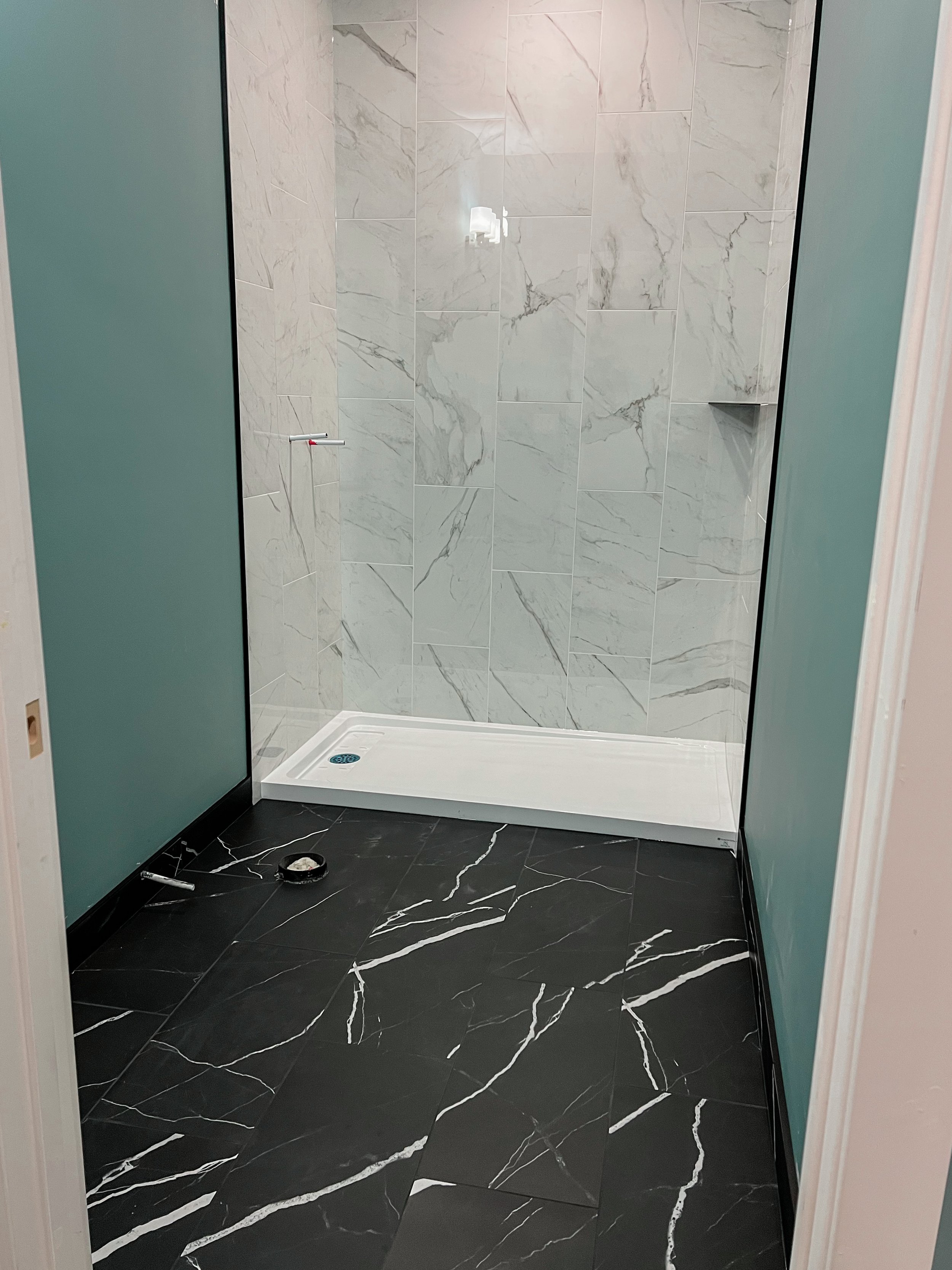 Bathroom with white tiled shower and black marble floor