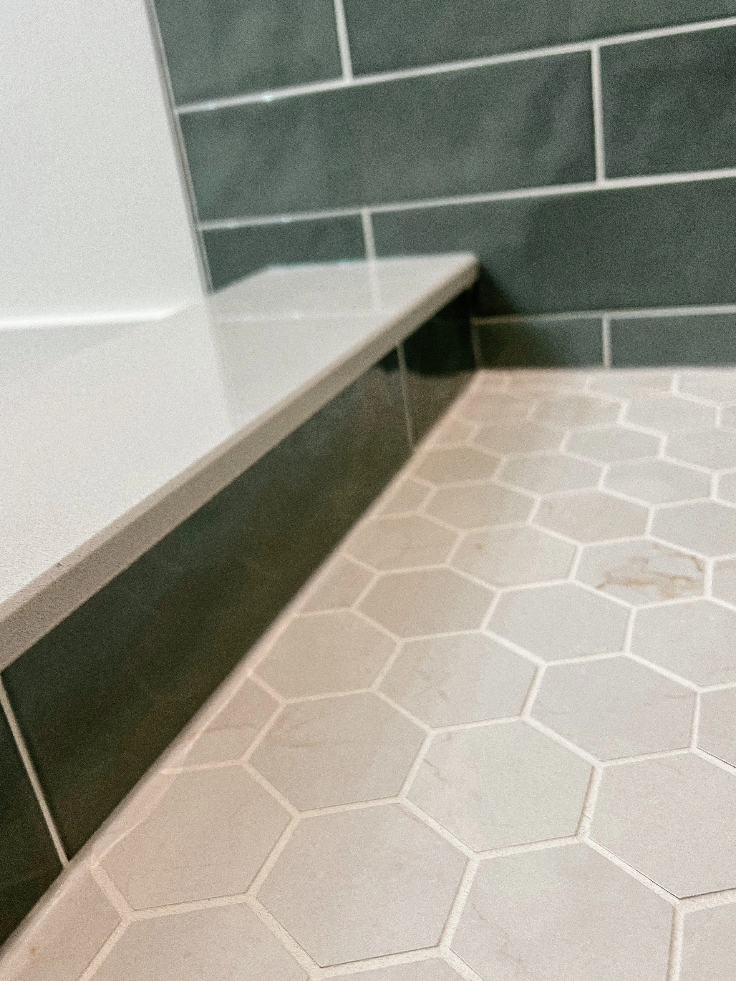 Bathroom corner with hexagonal floor tiles and green subway wall tiles