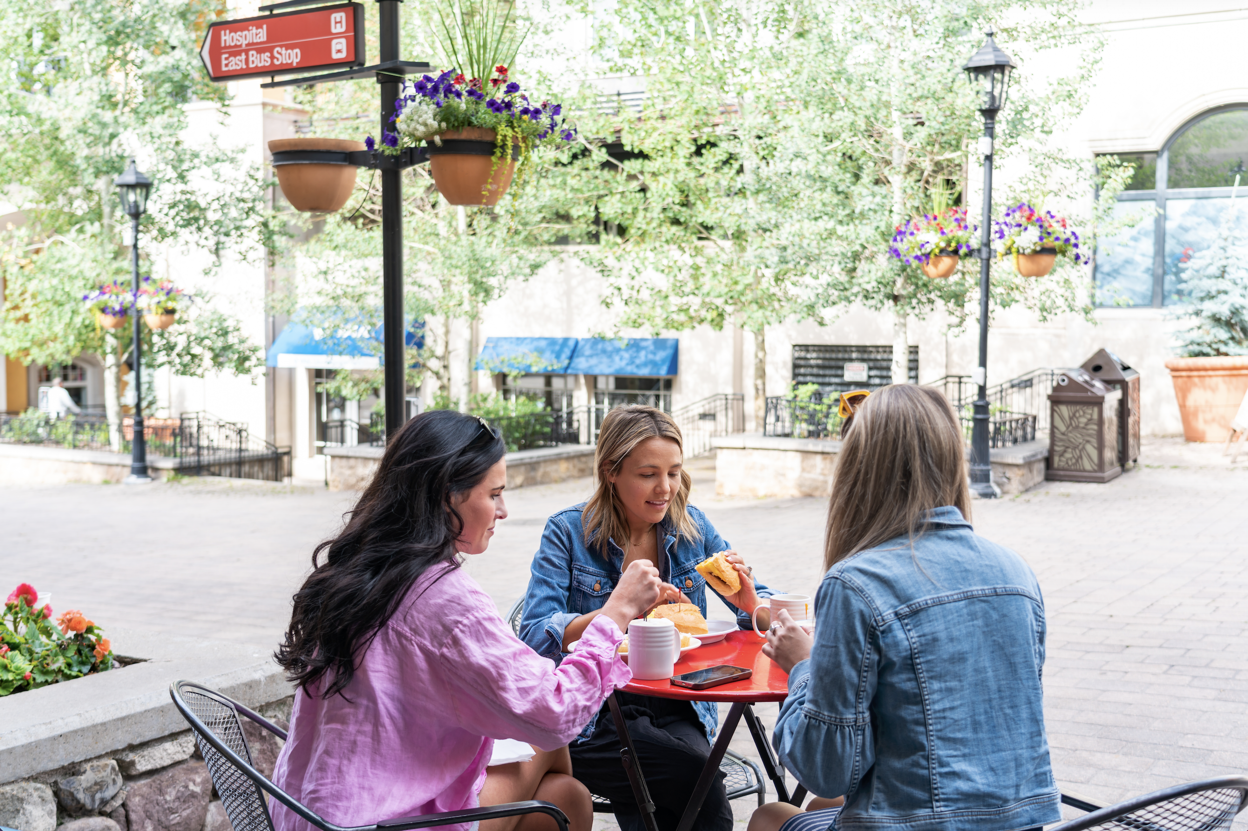Three people eating in Lionshead Village on a sunny day in Vail, Colorado.