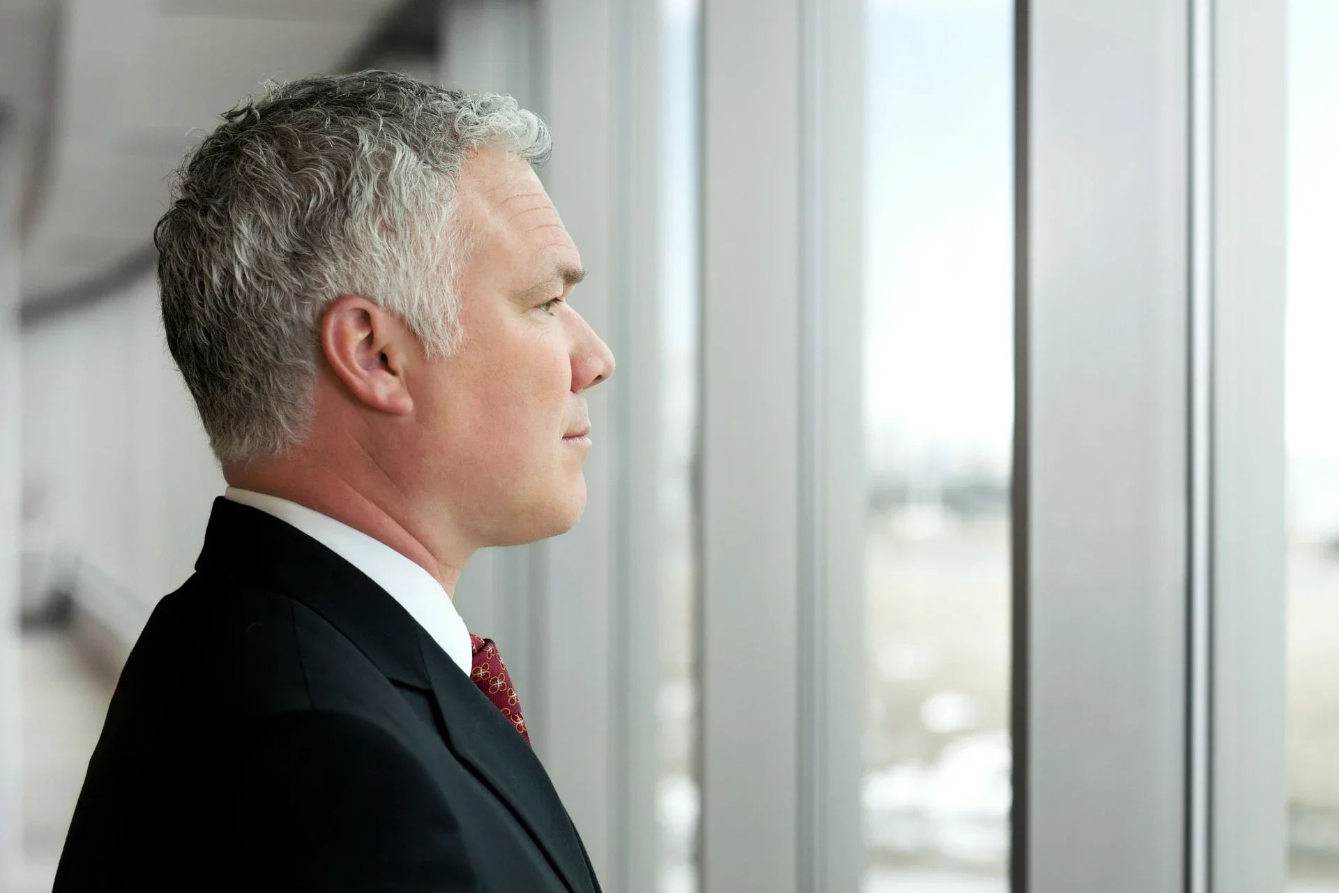 A CEO thoughtfully looking out the window of the office building