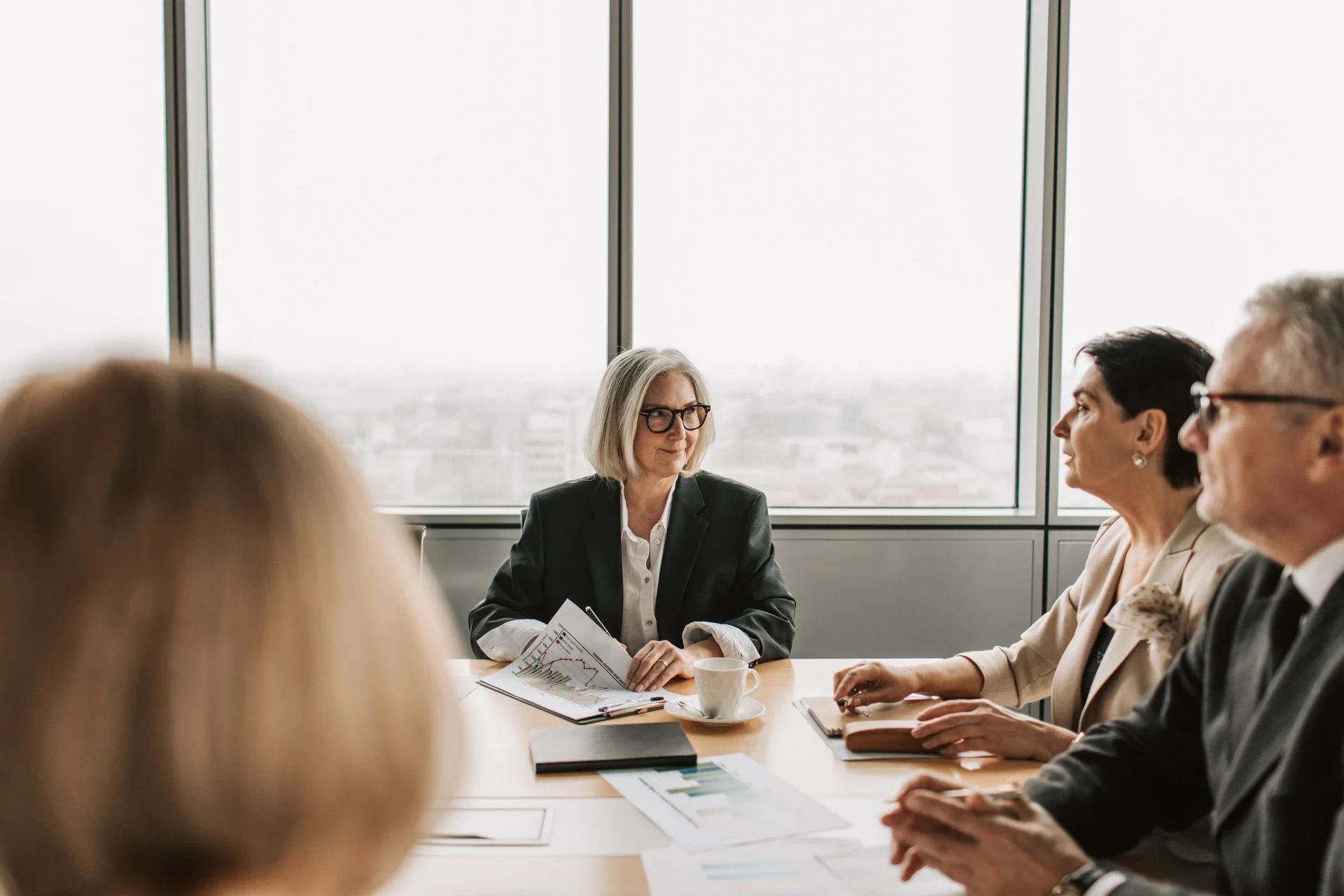 A group of professionals engaged in a business meeting inside a modern office boardroom