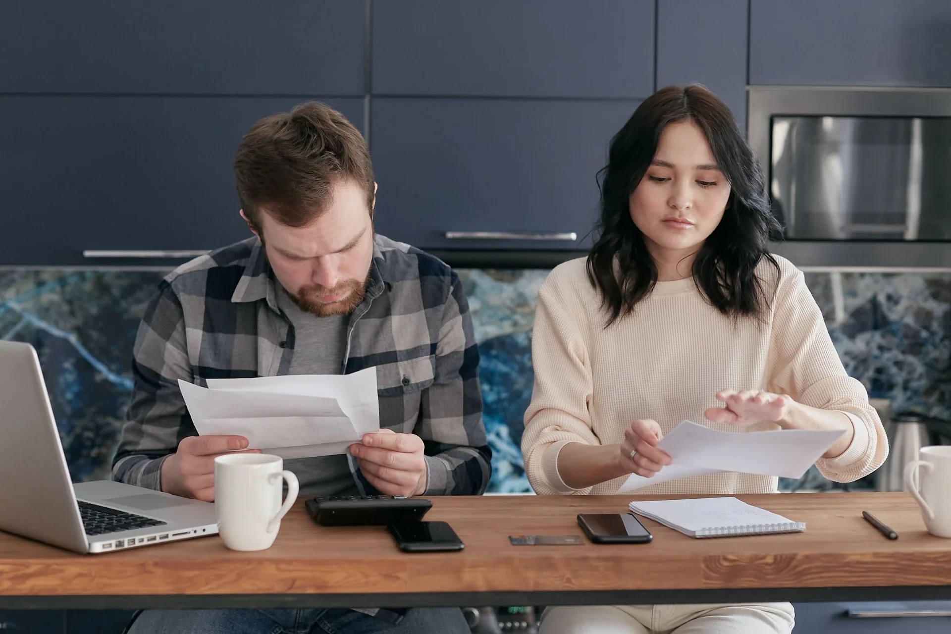 A couple reviews bills and manages finances on a kitchen table