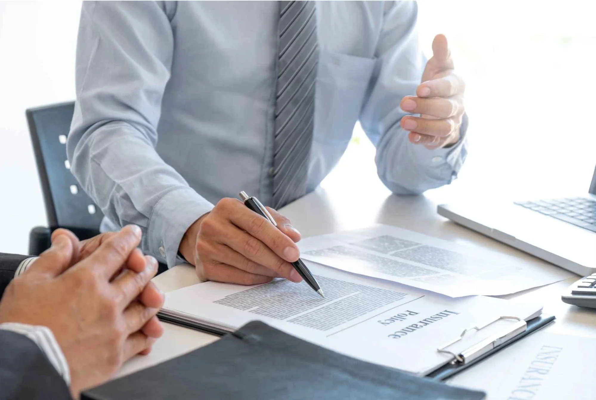 Business owner and advisor comparing whole life and universal life insurance policy documents at an office desk