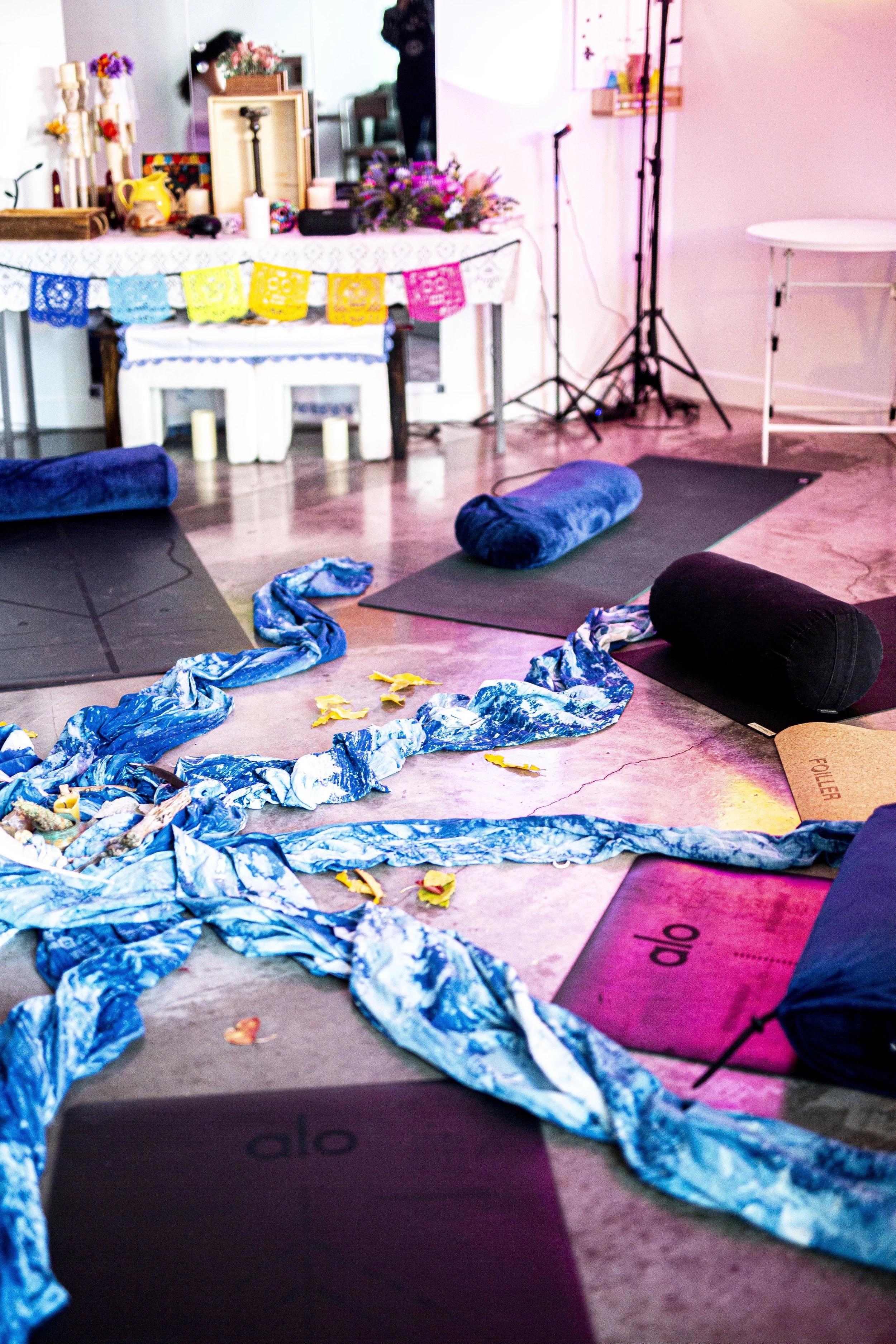 A circle of mats, with colorful fabric, and papel picado in the background.