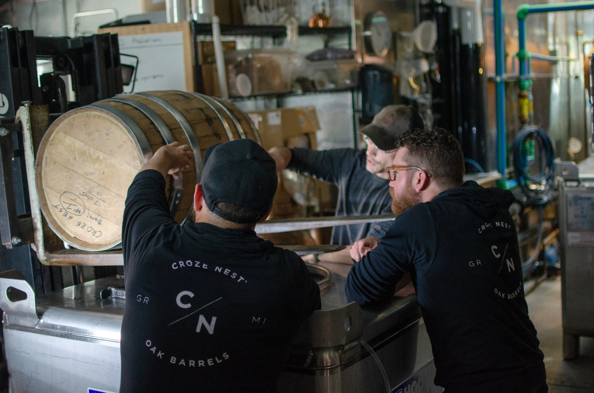 Croze Nest crew in branded shirts inspecting a signed oak barrel in the shop