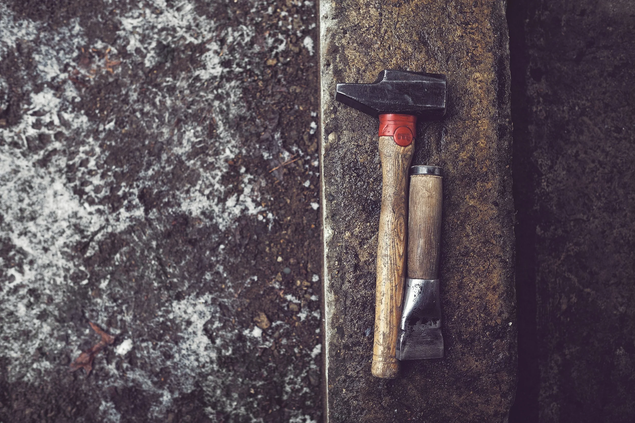 Cooper's hammer and chisel resting on a weathered stone slab
