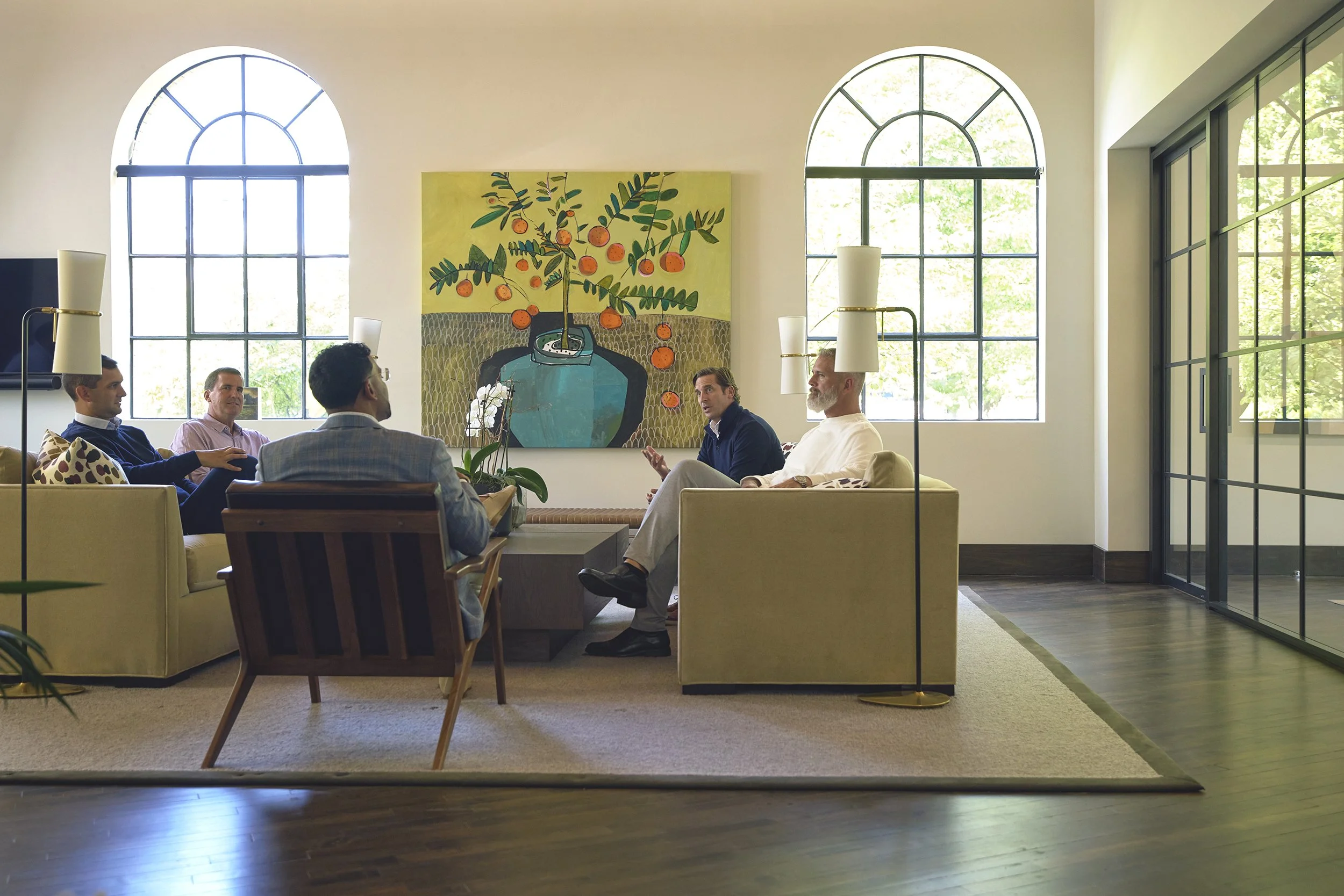 Five professionals in a strategy conversation in a bright lounge