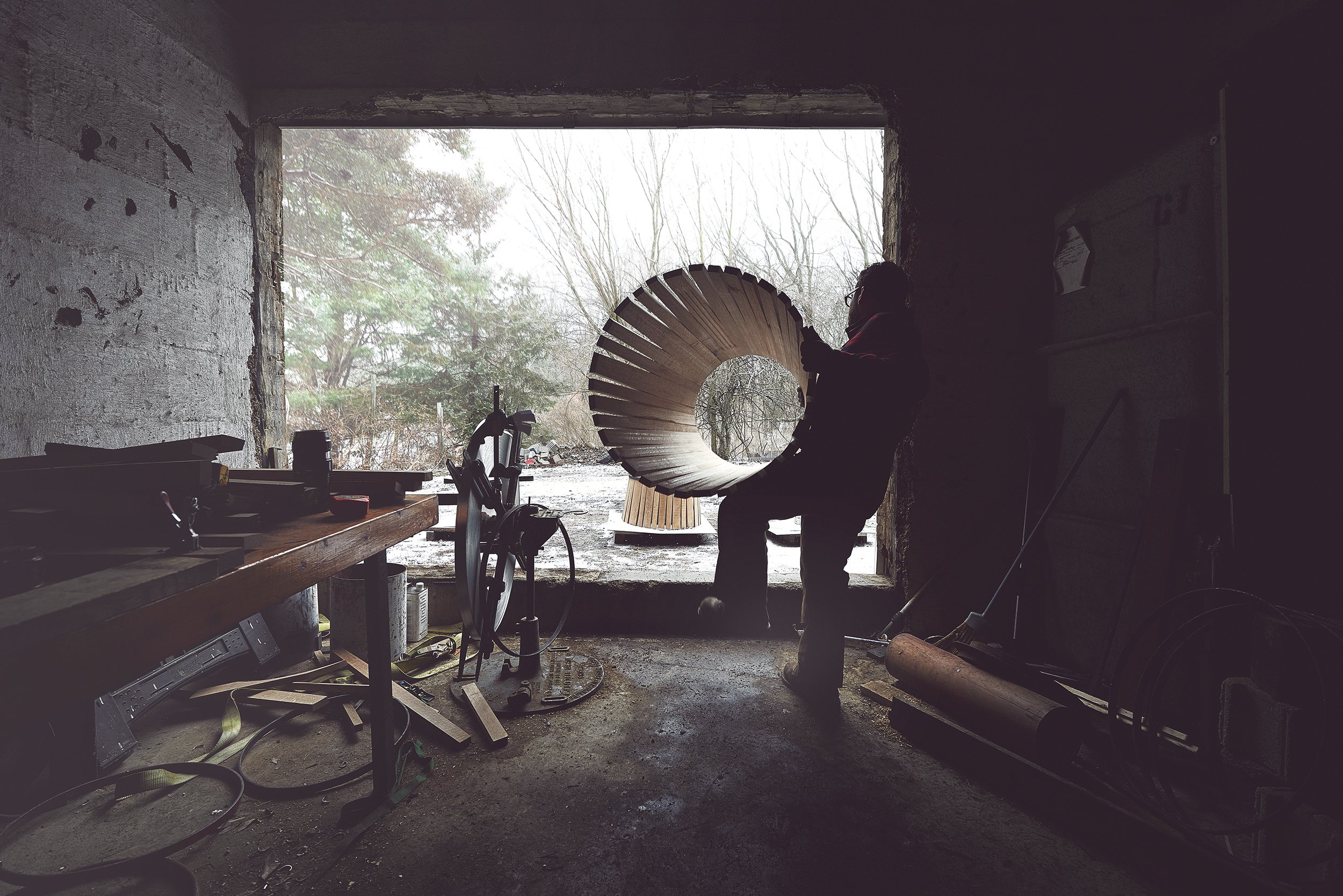 Cooper steadying a raised circle of oak staves in the workshop doorway
