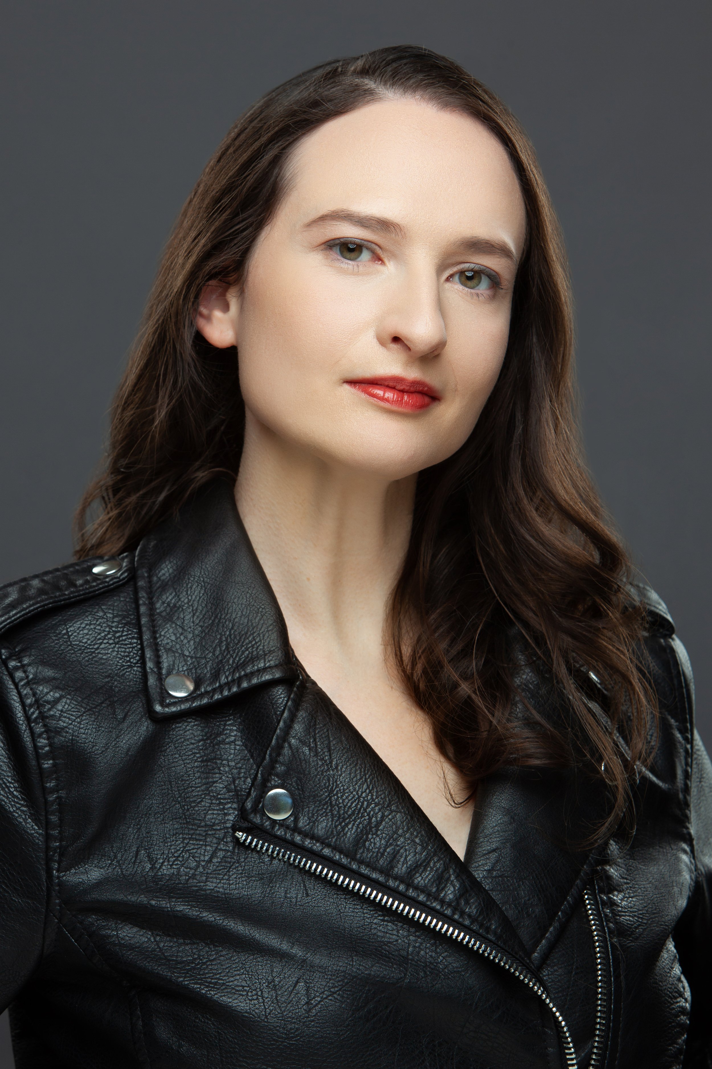 A headshot of a woman in a leather jacket looking at the camera seriously