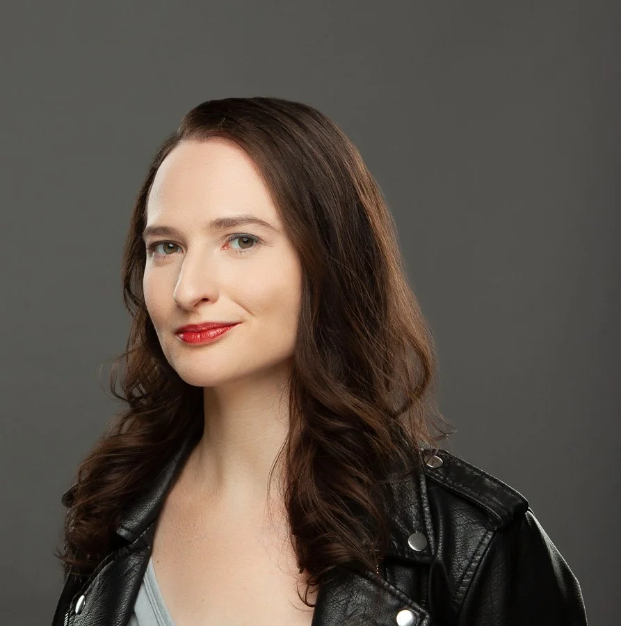A woman in a leather jacket smiling slightly