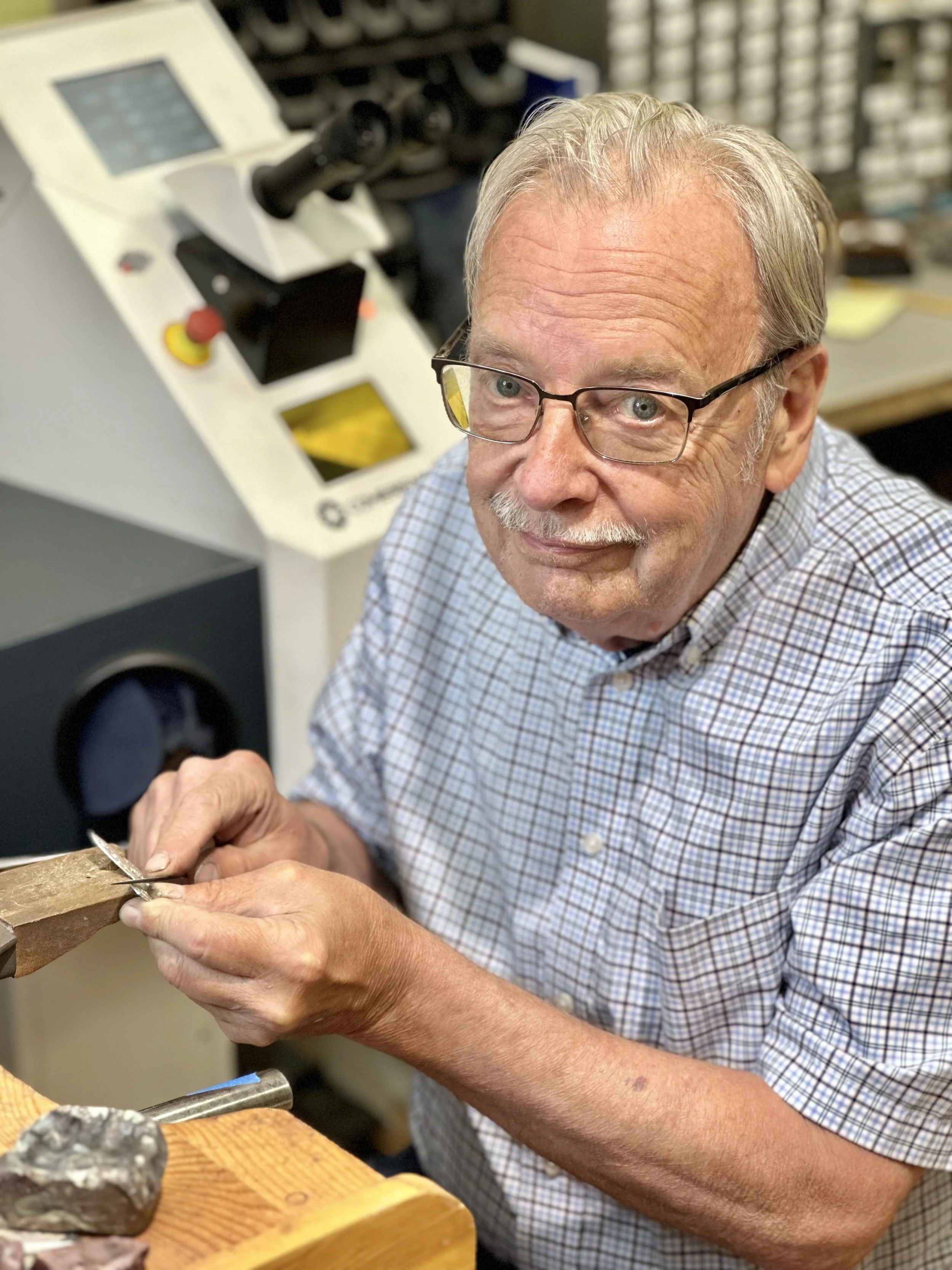 Artist James Cleland, owner and founder of Designs In Gold, sitting at the jewelers work bench