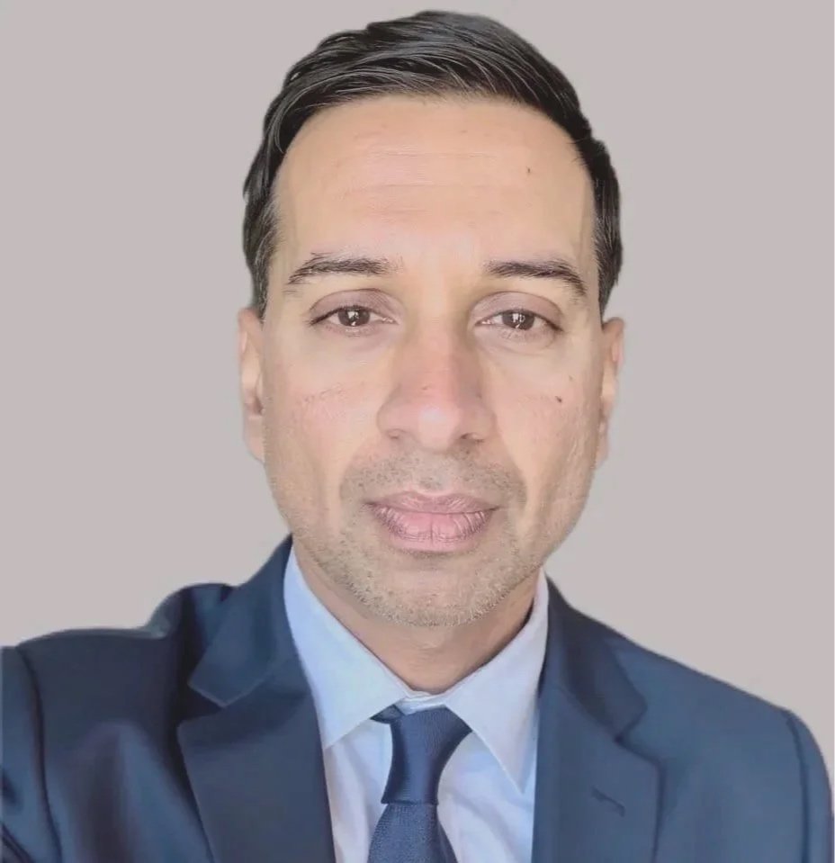 A professional headshot of Jimmy Swinder, in a dark suit and tie, with dark hair, looking directly at the camera against a plain, light-colored background. An official photograph, the real Jimmy Swinder