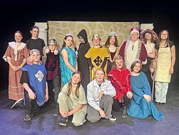 Group of students on stage posing after a show