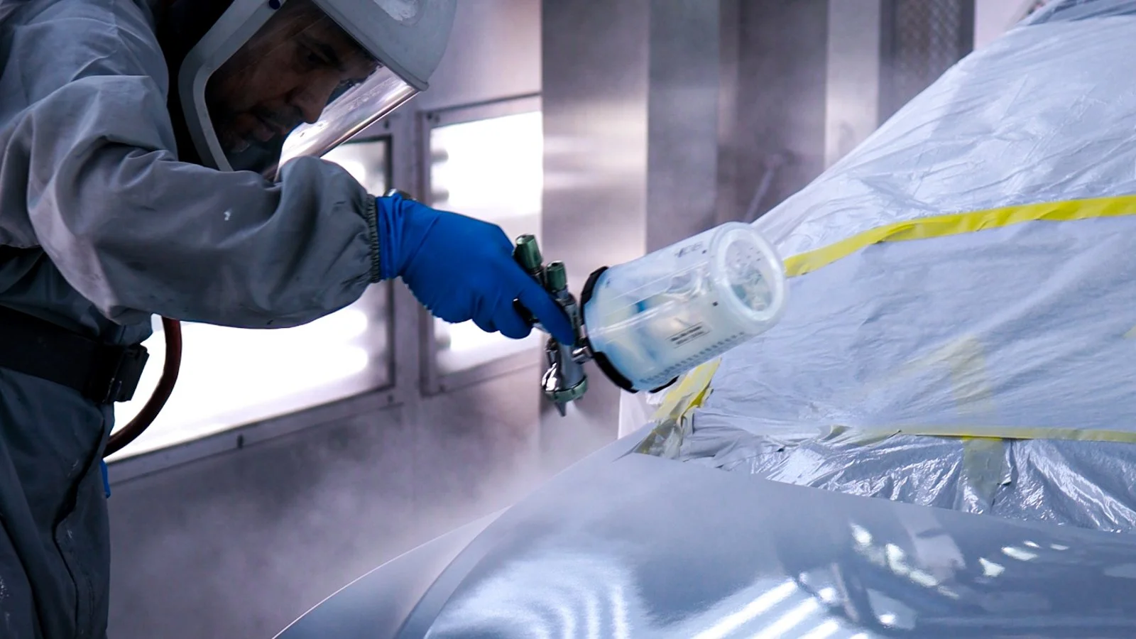 Auto body technician spraying paint during collision repair process at an Oxnard collision repair shop