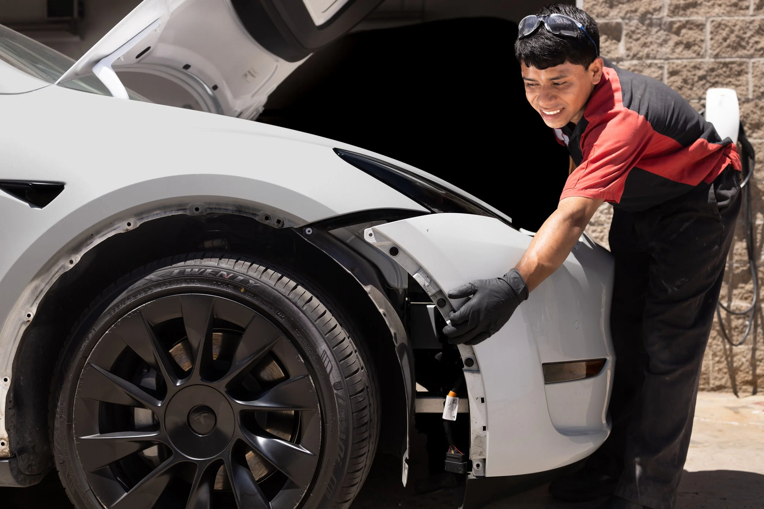 Tesla Model Y front bumper being removed during collision repair in Oxnard