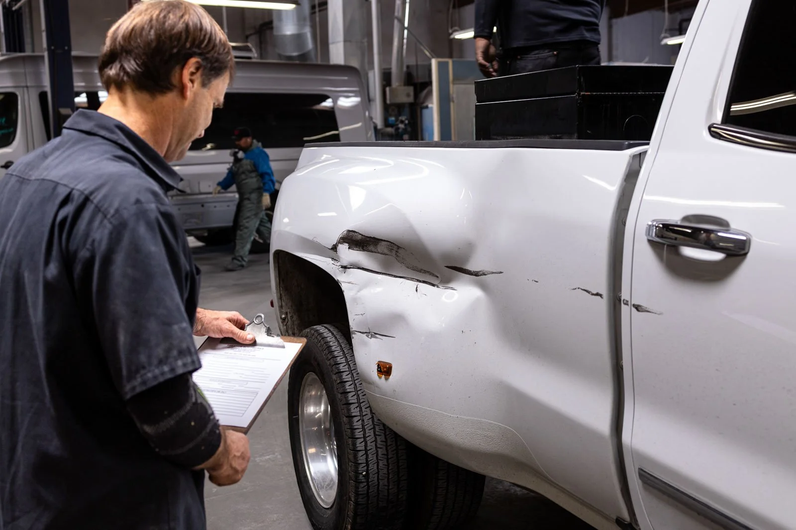Technician inspecting damaged fender after car accident at collision repair shop in Oxnard
