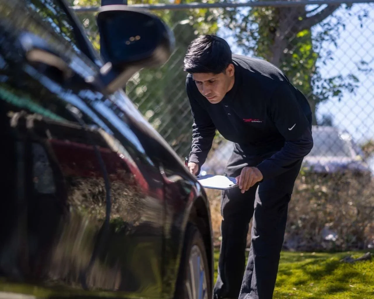Technician inspecting vehicle structural alignment during collision repair in Oxnard