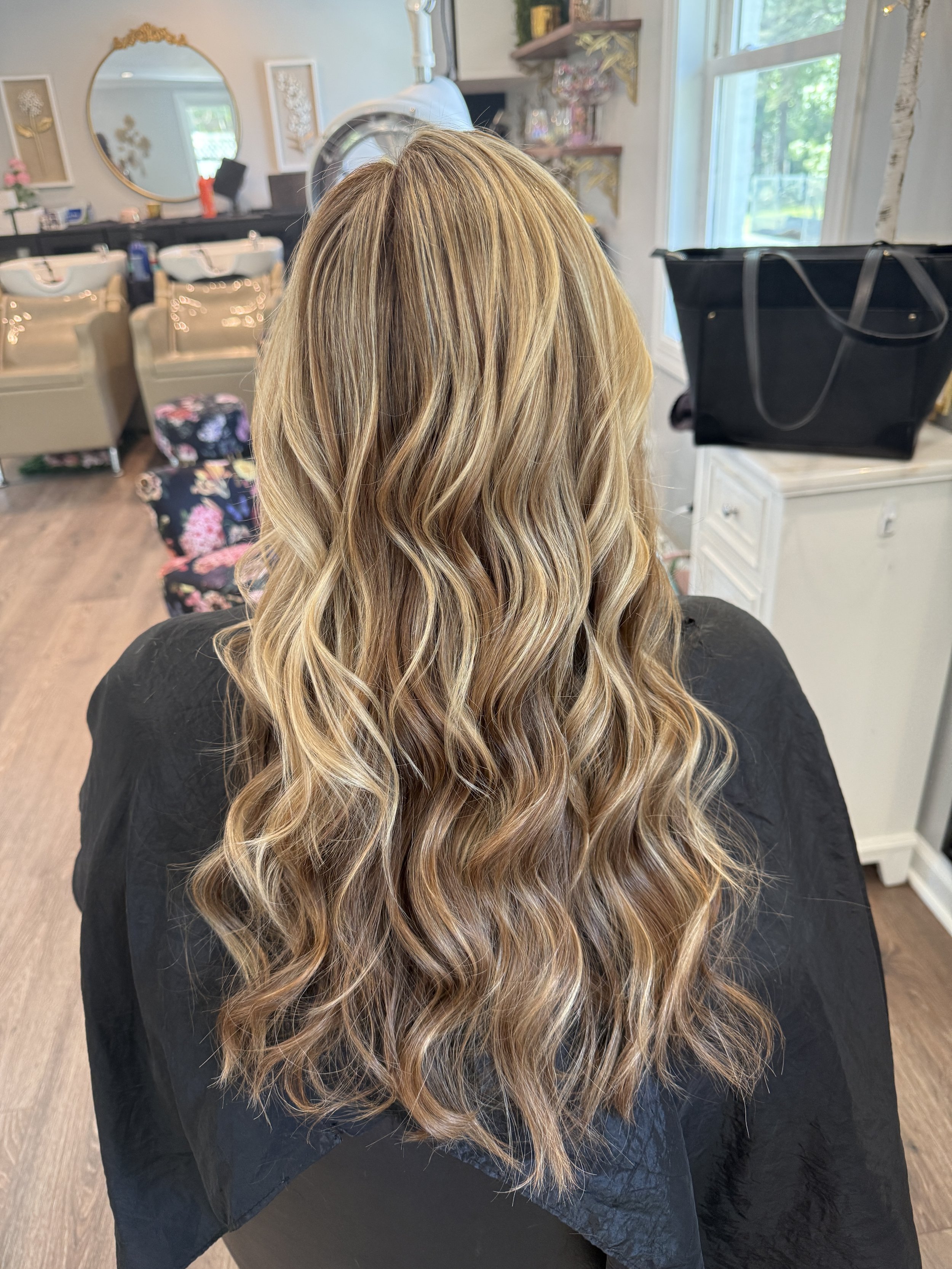 Back of a woman with long, wavy, blonde hair in a hair salon.