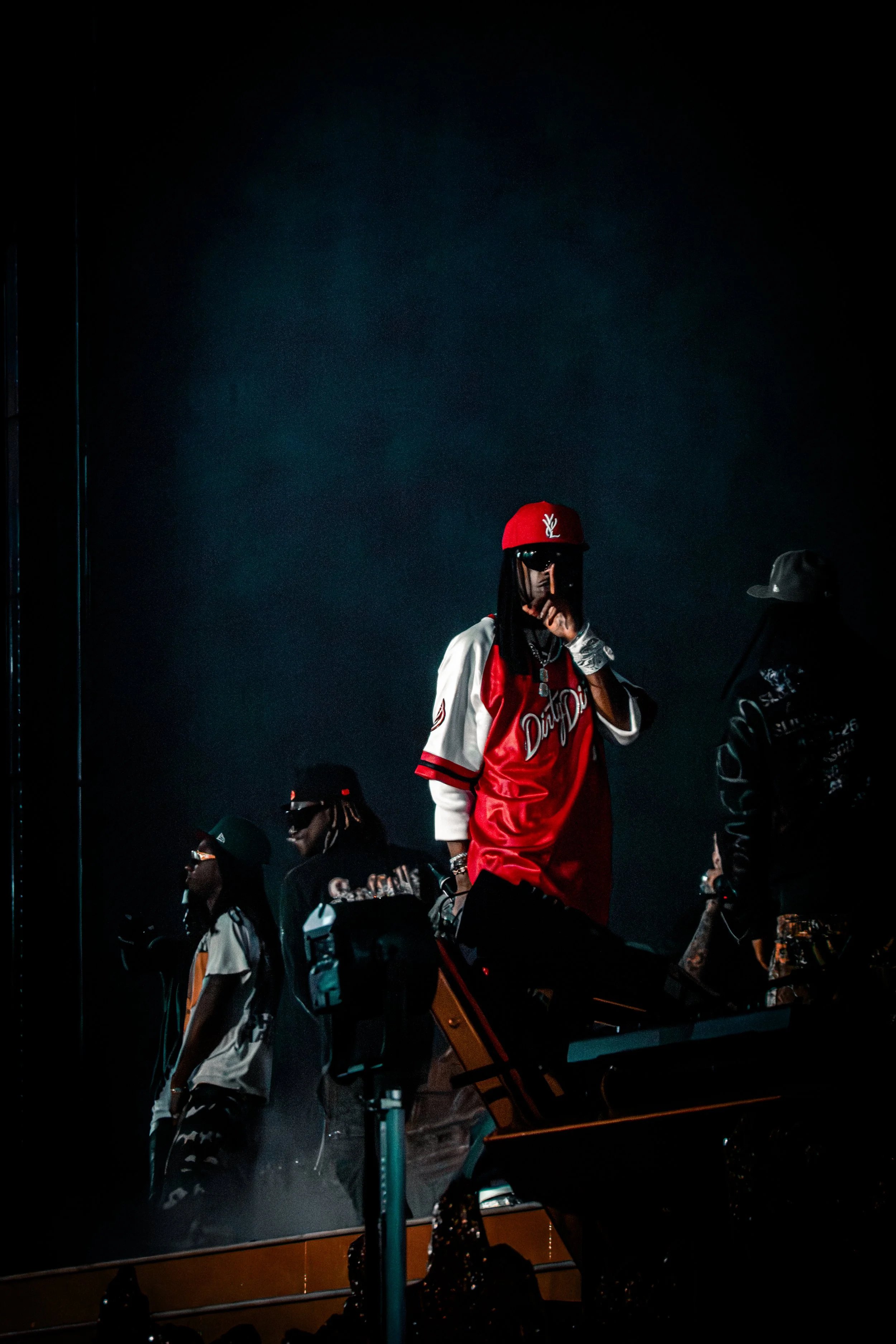 Concert photography of a rapper/performer on stage under dramatic lighting and smoke effects.
