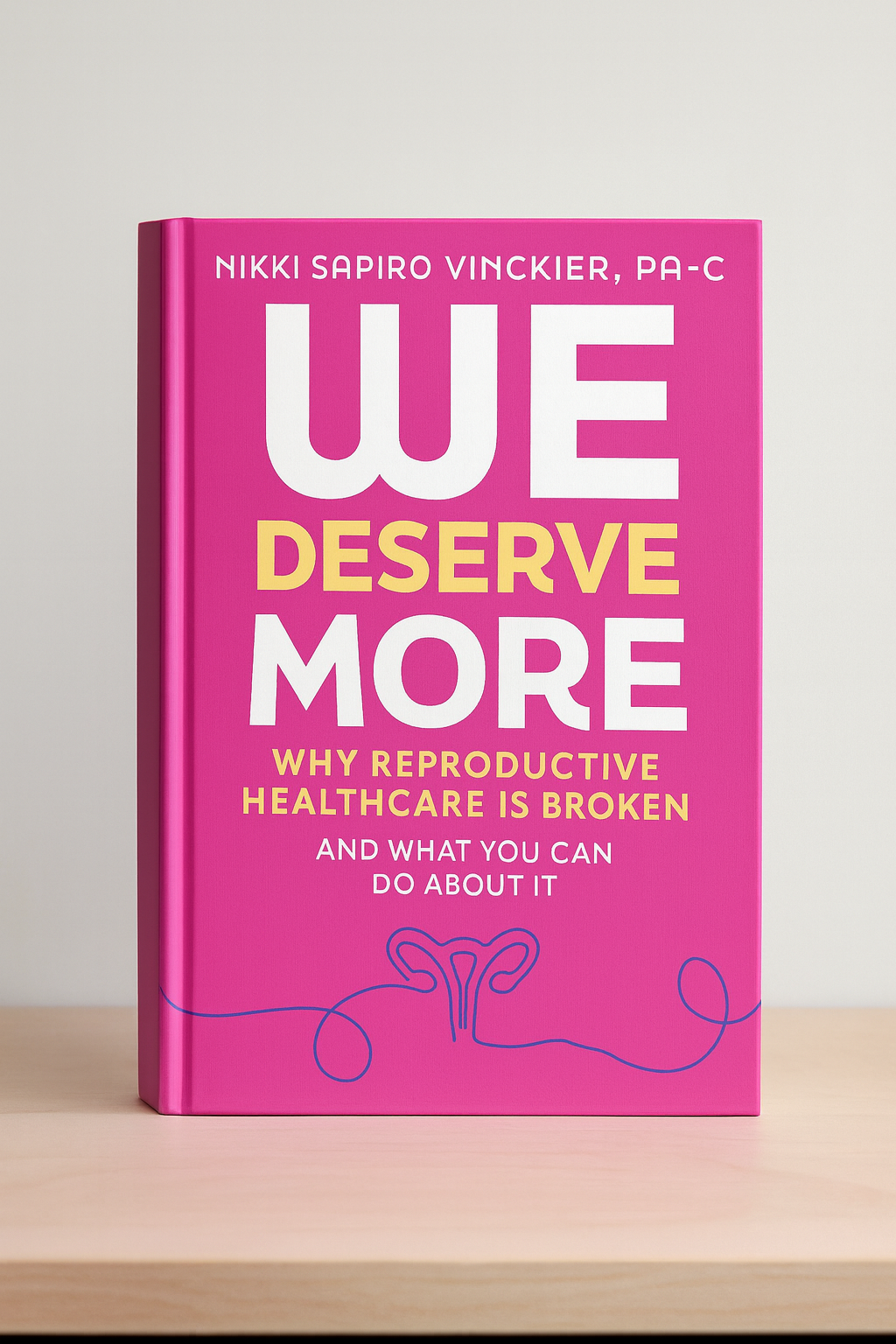 Pink book titled 'We Deserve More' by Nikki Sapiro Vinckier, PA-C, with subtitle about reproductive healthcare, on a light-colored table against a plain background.