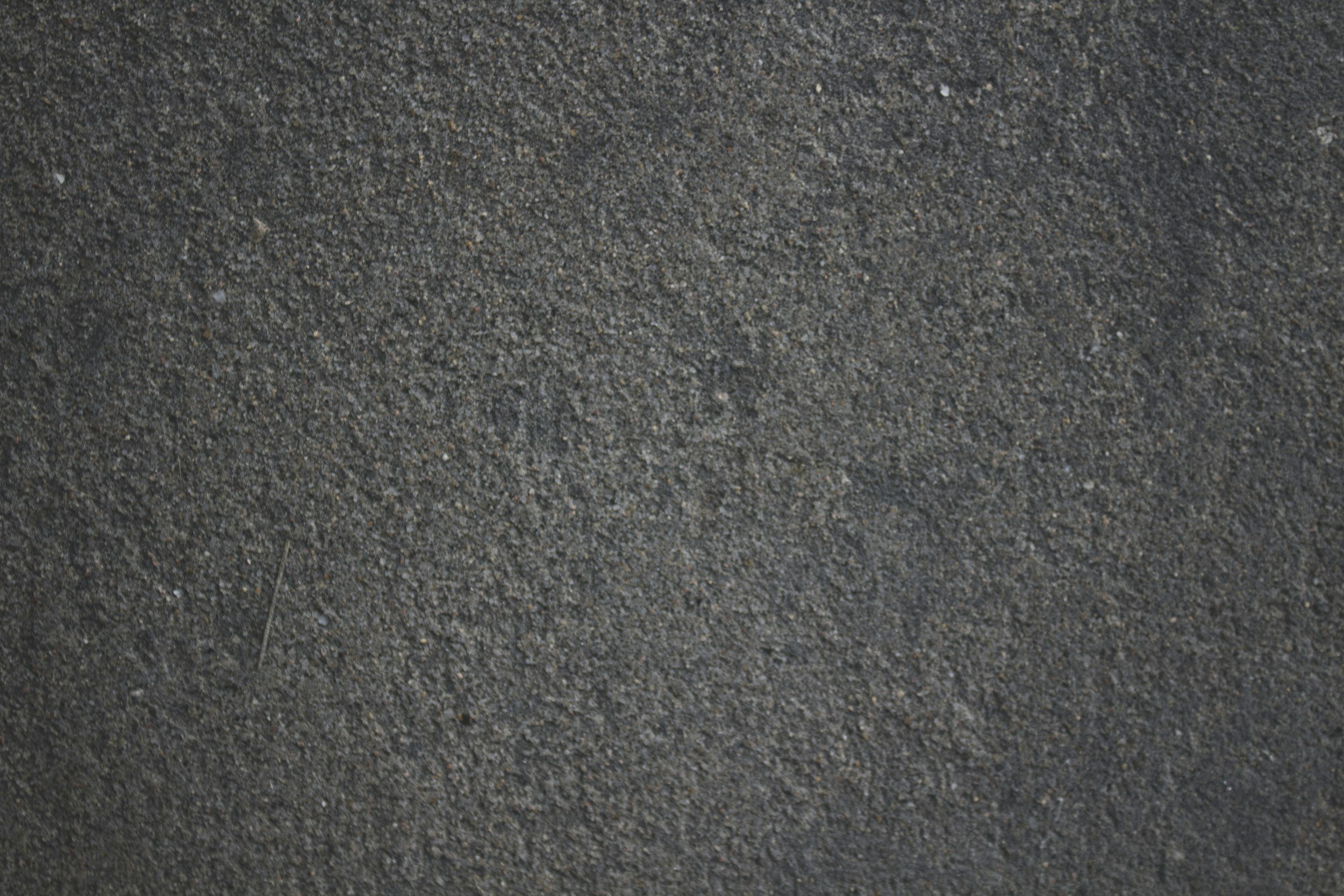 Close-up of a textured dark gray asphalt pavement surface.
