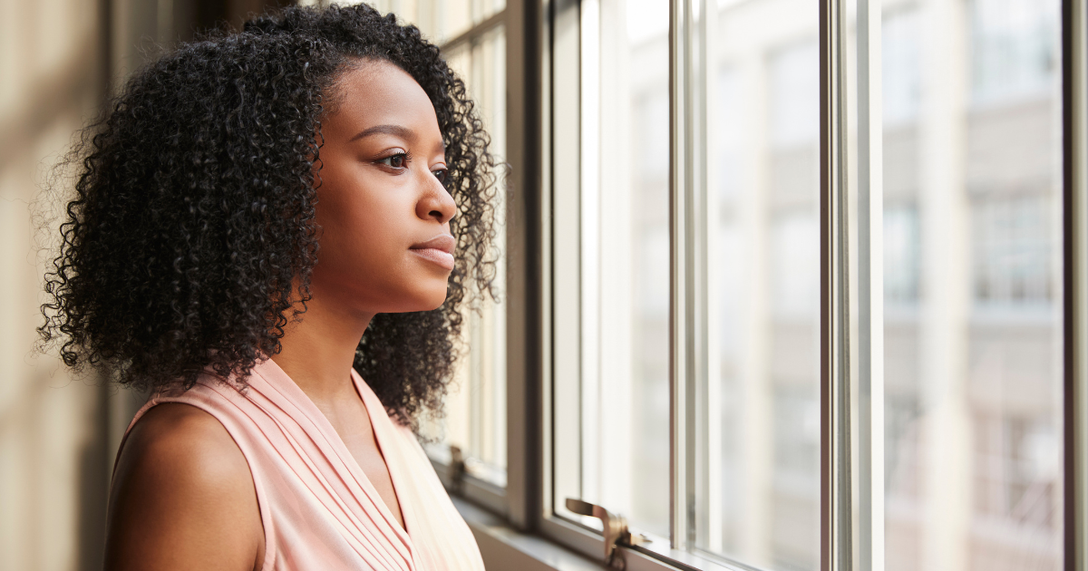 Business owner looking out a window in reflection, representing gratitude and focus