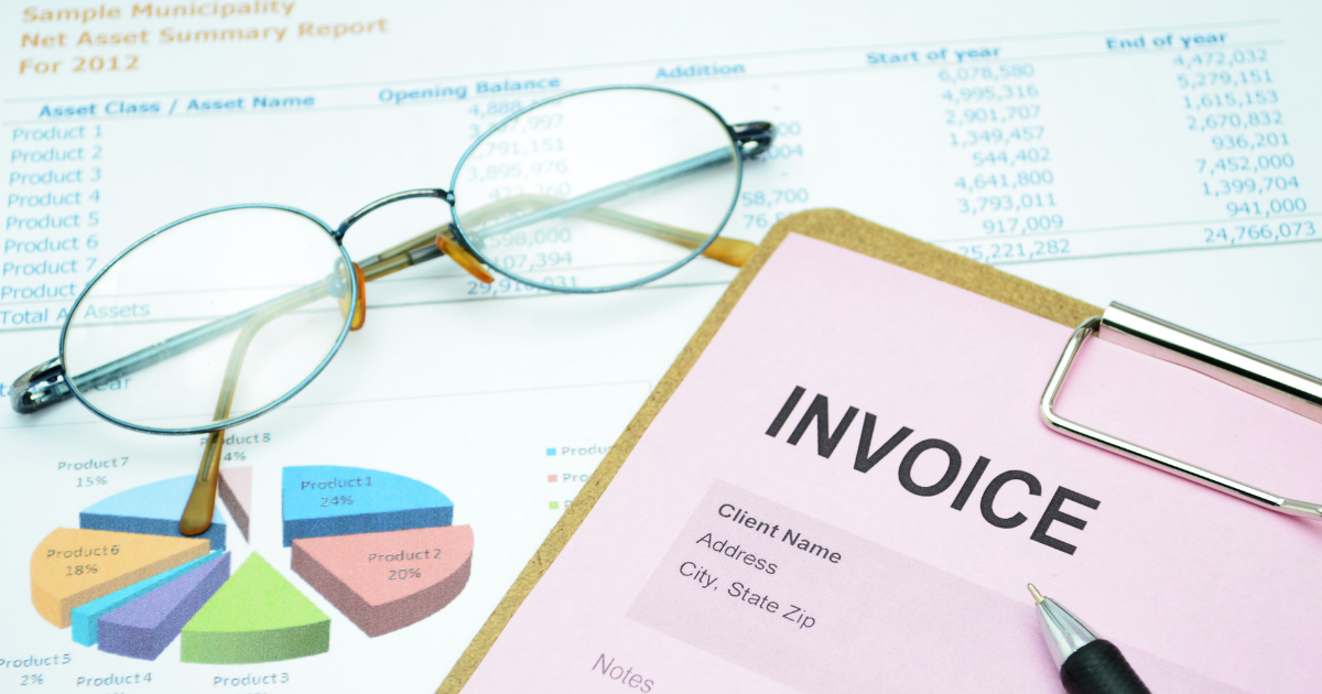 Invoice, financial report, glasses, and pen on a desk representing bookkeeping, expense tracking, and financial visibility for a small business.