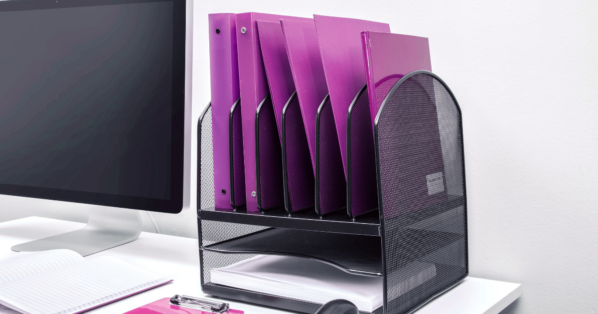 Organized office file folders in purple binder sleeves on a clean desk, symbolizing a simplified physical workspace for subcontractors.