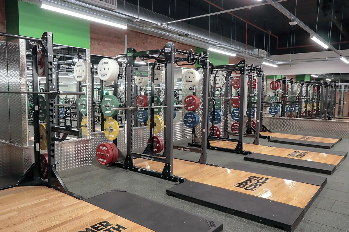 Olympic lifting platforms and squat racks at Buzz Gym Oxford with barbells and weight plates.