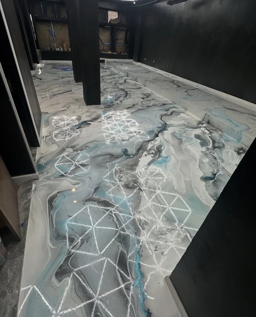 Marble-style tile floor with white geometric patterns, a black wall, and glass walls in the background.