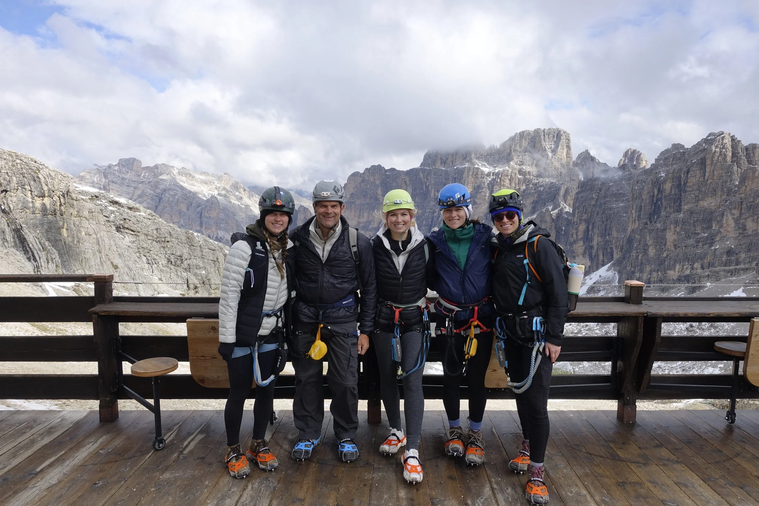Happy group of clients at Rifugio Lagazuoi before the via ferrata in the tunnels, with mountain guide Filippo during a Dolomites Safari. 