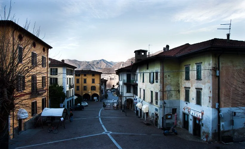 Empty European street with colorful buildings and mountains in the background.