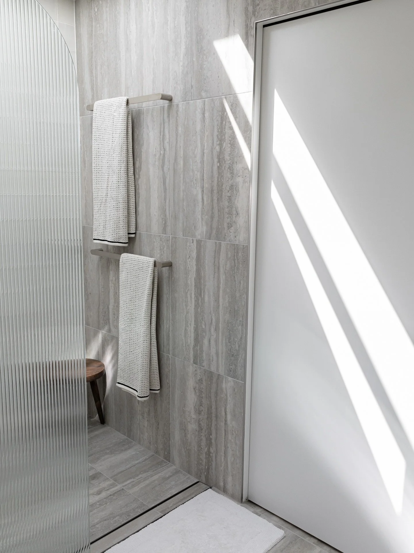 MAIN BATHROOM - 

Our main bathroom is designed as a calming, spa-like sanctuary, blending modern minimalism with warmth and texture. Drenched with a grey Travertine tile and feature Zellige Tile in the shower space. With an opening large skylight wh