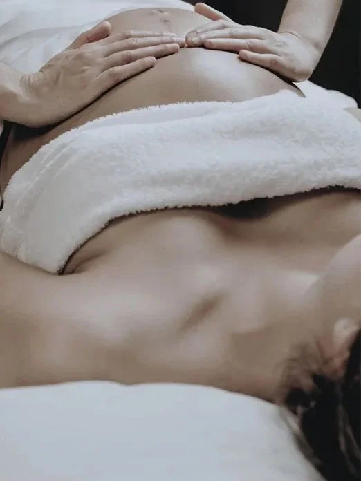 Person receiving a massage on their abdomen, lying down with hands on their stomach.