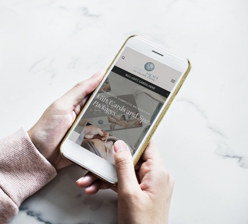 Person holding a smartphone displaying an instant digital spa gift card for The Spa at Yellow Creek.
