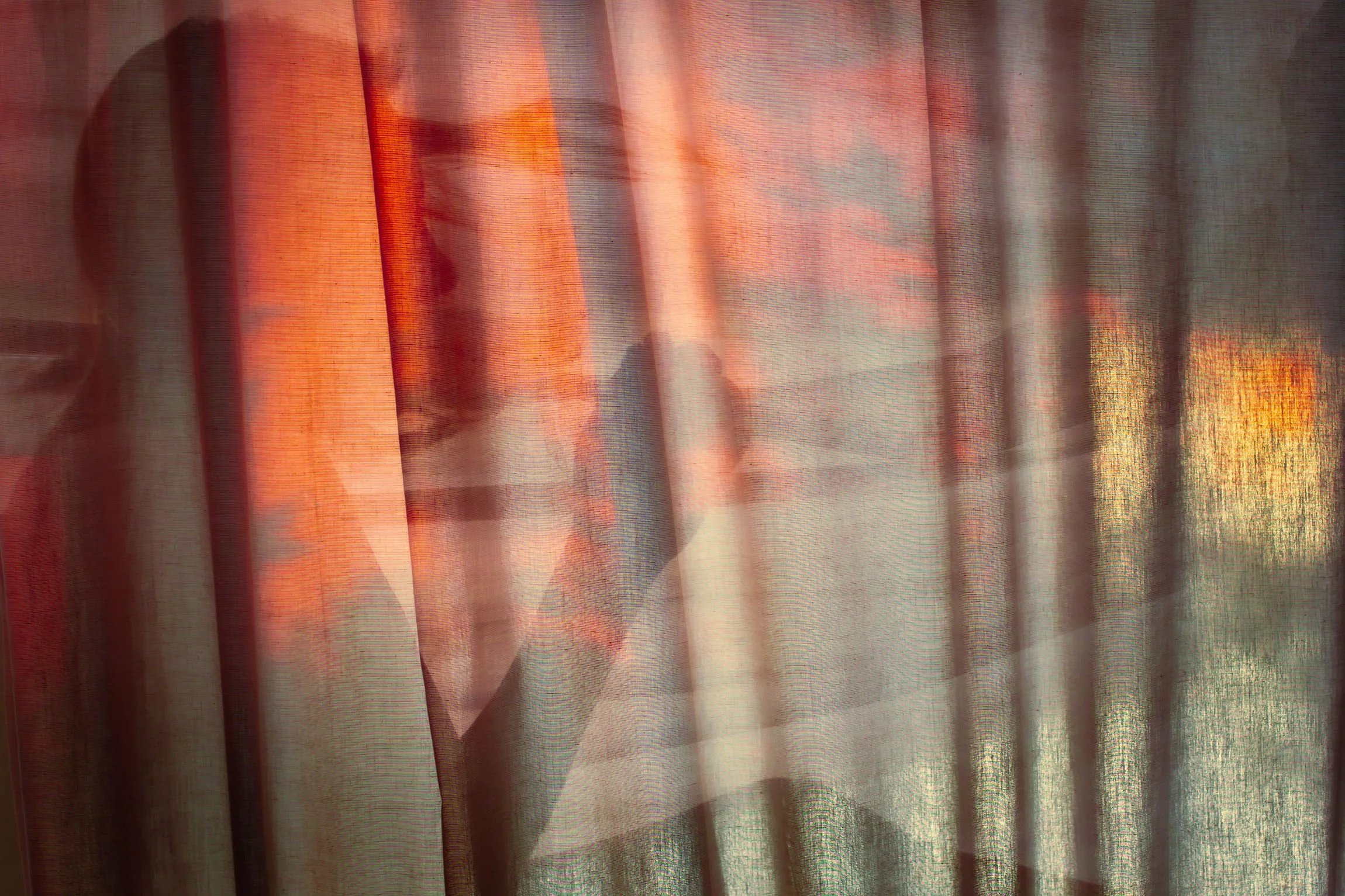 Woman behind sheer curtain in soft warm light