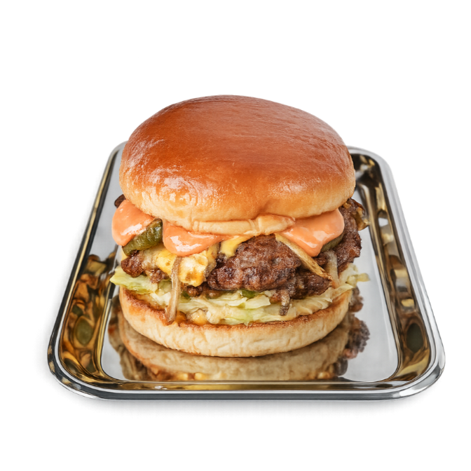 Cheeseburger with lettuce, grilled onions, and sauce on a bun, served on a metal tray.